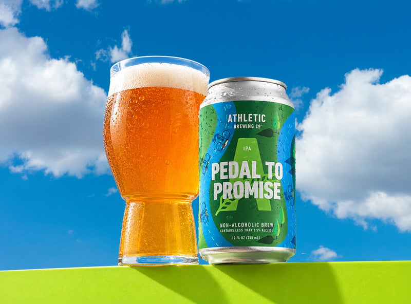 pedal to promise can and glass on a green ledge with blue sky background