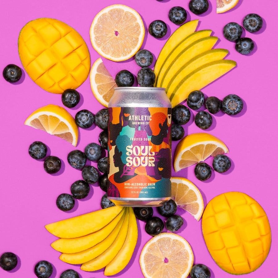 A can of soul sour laying down on fruits, mango, lemon and blueberrry.