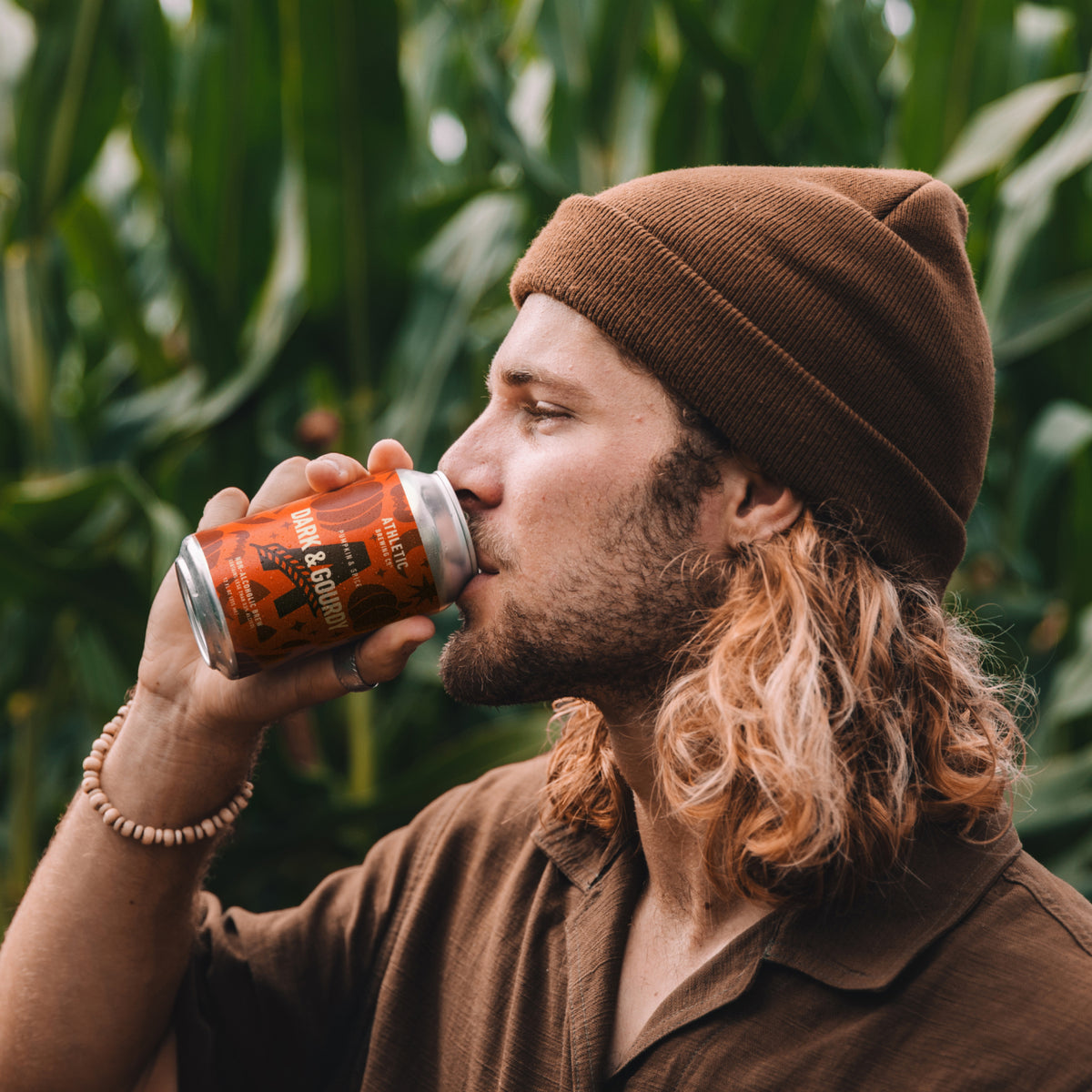 a mand drinking a cold dar&groudy at a corn field