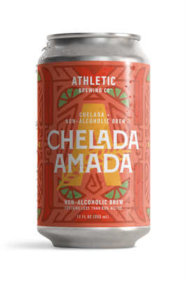 12 fl oz can of Athletic Brewing Chelada Amada non-alcoholic brew on a white background. The can features a coral-red label with a bold geometric pattern, lime slice illustrations, a large gold “A,” and the product name “Chelada Amada” in white lettering. Condensation droplets cover the can, emphasizing a cold, refreshing beverage.